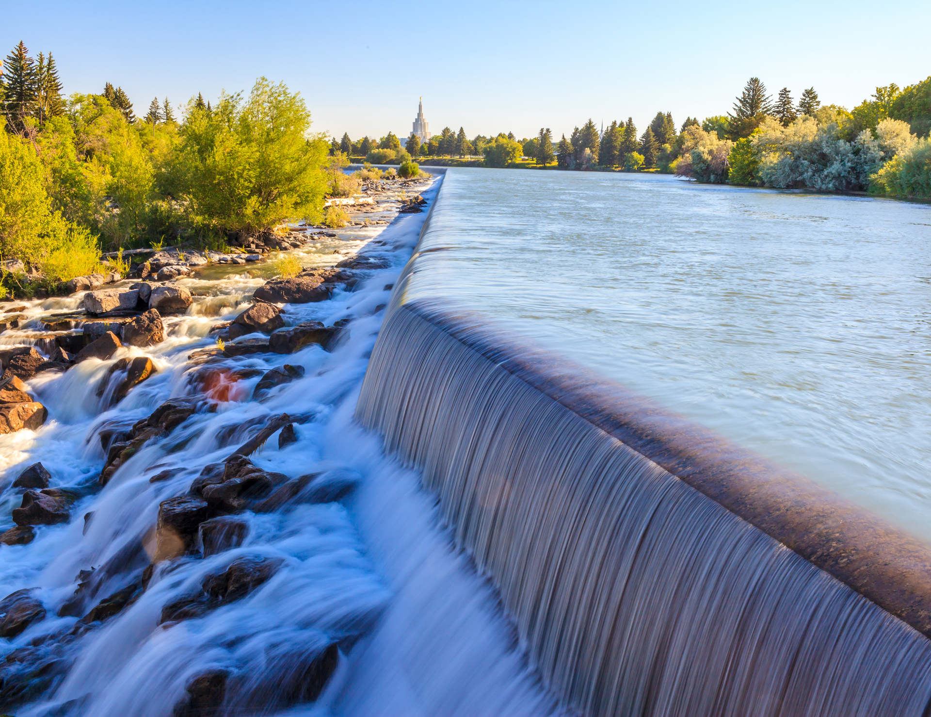 The falls on the Snake River with the Idaho Falls Idaho Temple in the distance in Idaho Falls, ID.